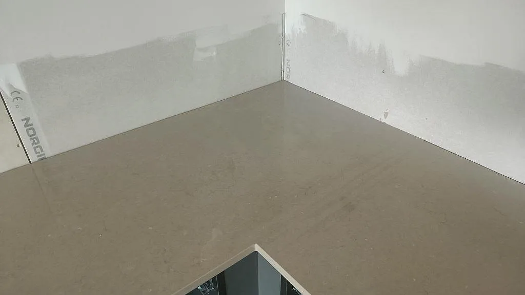 Köksbänkskiva i polerad Silestone Coral Clay med öppna lådskenor under montering i ett kök i Bunkeflostrand.