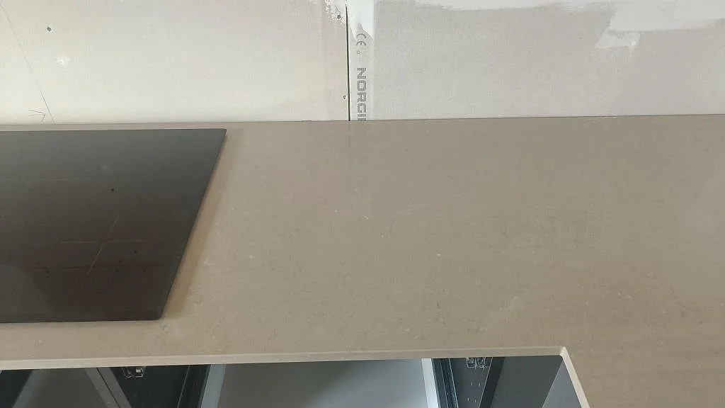 Köksbänkskiva i Silestone Coral Clay, polerad taupe kvartskomposit, med infälld induktionshäll mot ännu omålad vägg i ett kök i Bunkeflostrand.
