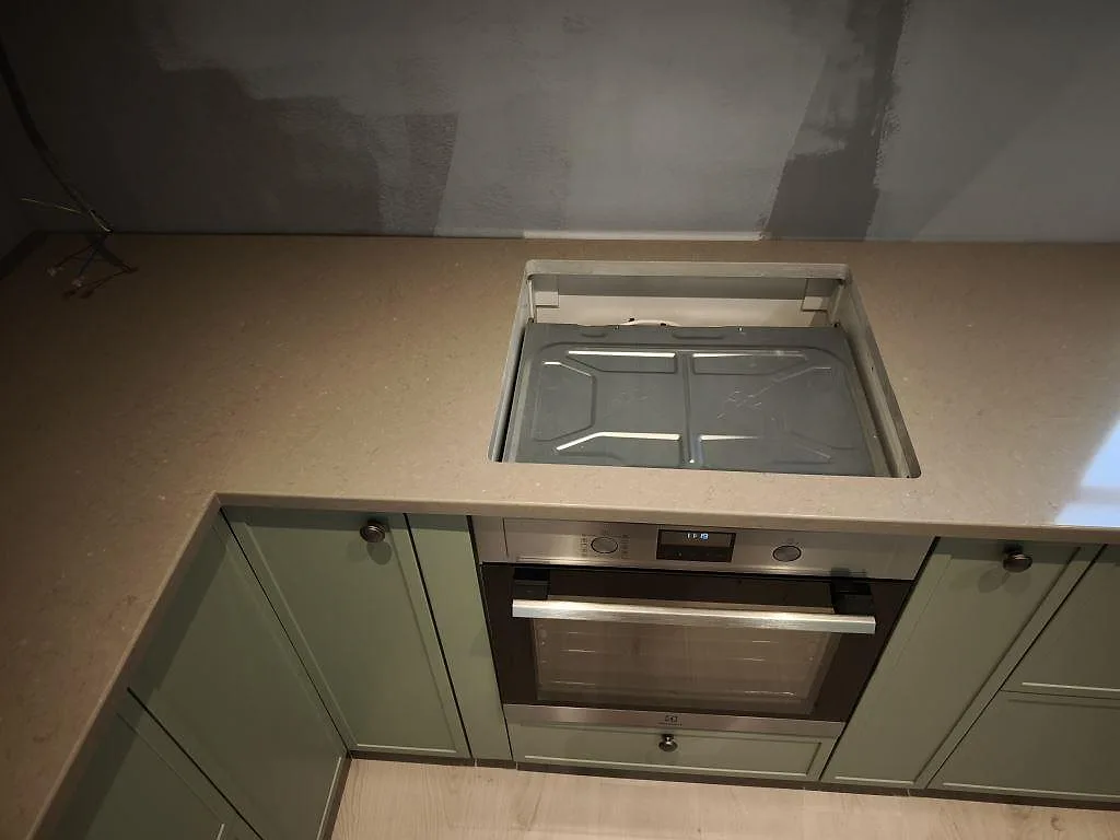 Köksbänkskiva i polerad Silestone Coral Clay med hällöppning över ugn och ljus kvartskomposityta i Dalby.