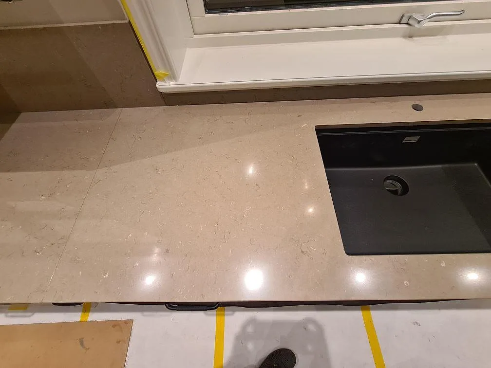 Diskbänksdel i polerad Silestone Coral Clay med svart diskho och förborrat hål för blandare i Enköping.