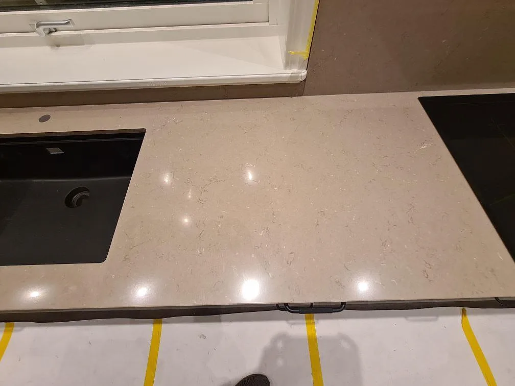 Polerad Silestone Coral Clay mellan svart diskho och svart induktionshäll i kök i Enköping.