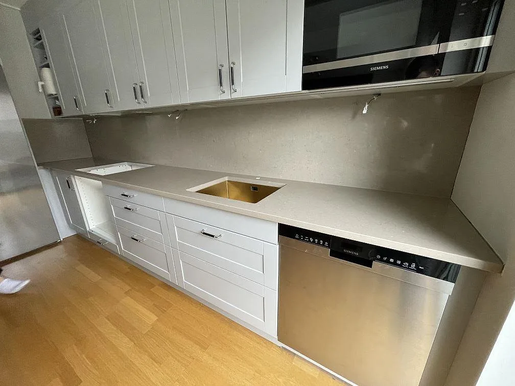 Köksbänkskiva i Silestone Coral Clay, polerad komposit, med synlig diskho, hällöppning och stänkskydd i ett kök i Enköping.