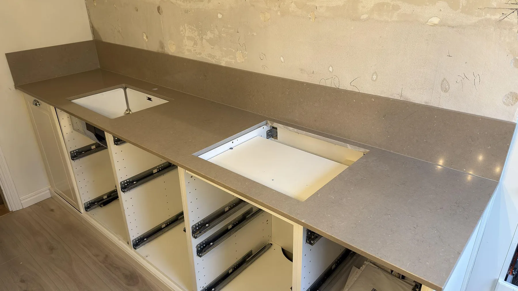 Polerad Silestone Coral Clay som köksbänkskiva med uppvikt stänkkant, diskho och hällurtag i Enskede.