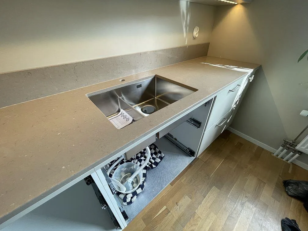 Närbild på diskzonen i polerad Silestone Coral Clay, med rostfri diskho och låg stänkkant i ett kök i Enskededalen.