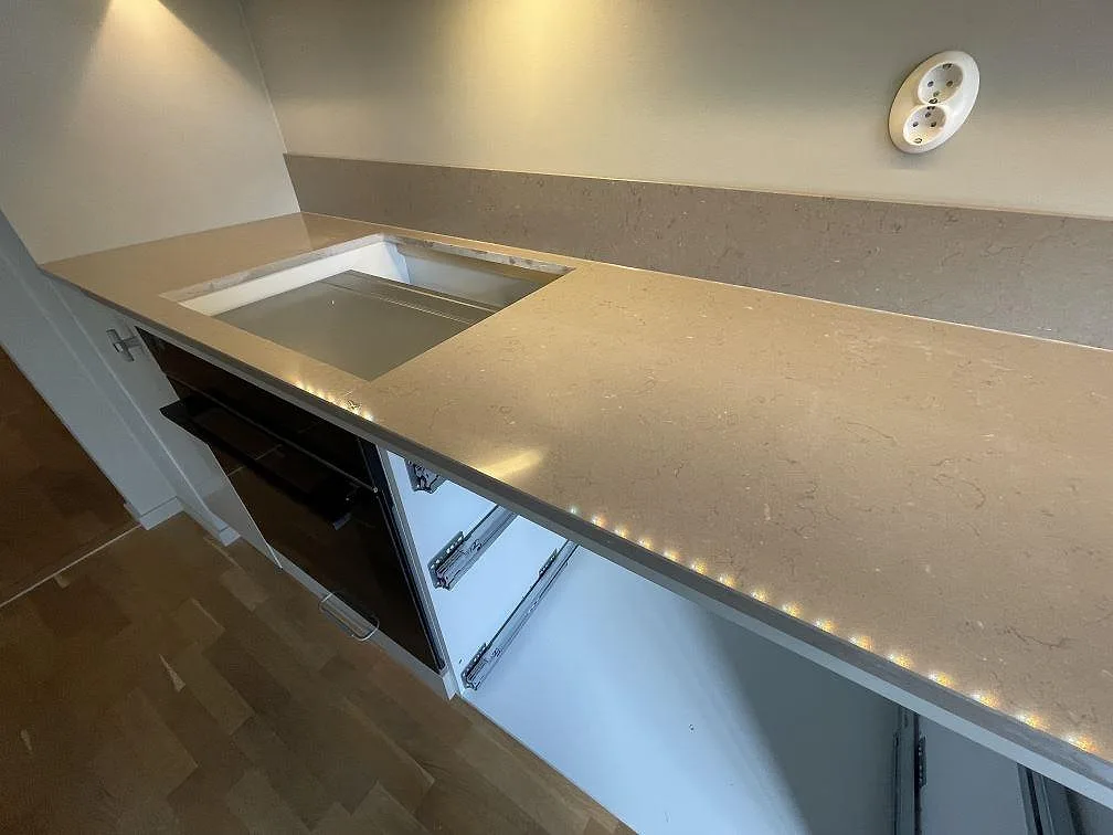 Polerad Silestone Coral Clay som köksbänkskiva med förberedd hällöppning och stänkkant längs väggen i Enskededalen.