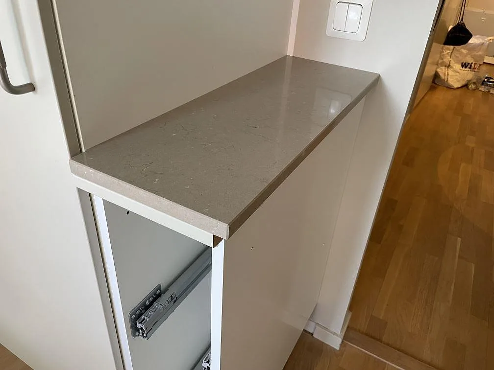 Mindre bänkskiva i polerad Silestone Coral Clay, monterad på vit stomme i bostaden i Enskededalen.