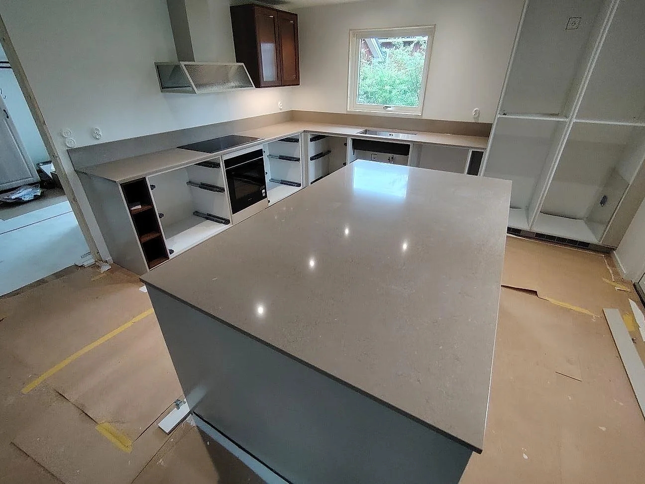 Köksbänkskiva och stor köksö i polerad Silestone Coral Clay kvartskomposit med U-formad bänk, induktionshäll och låg stänkkant i Eskilstuna.