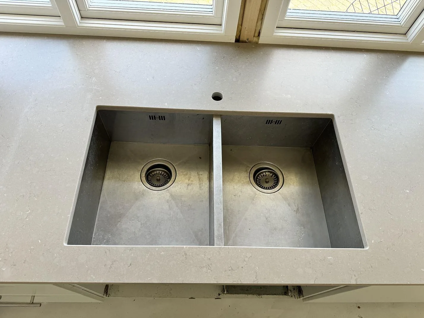 Närbild på underlimmad dubbelho i rostfritt stål monterad i matt Silestone Coral Clay i ett kök i Falsterbo.