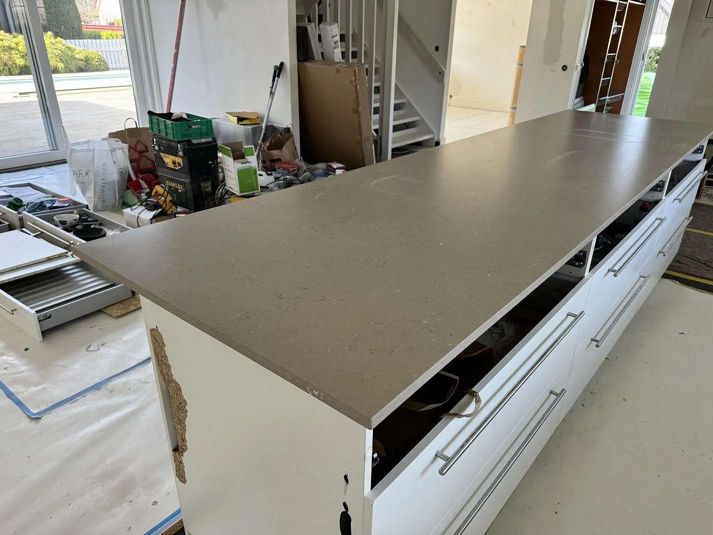 Stor köksö i matt Silestone Coral Clay, 20 mm, monterad på vita köksstommar i Falsterbo.
