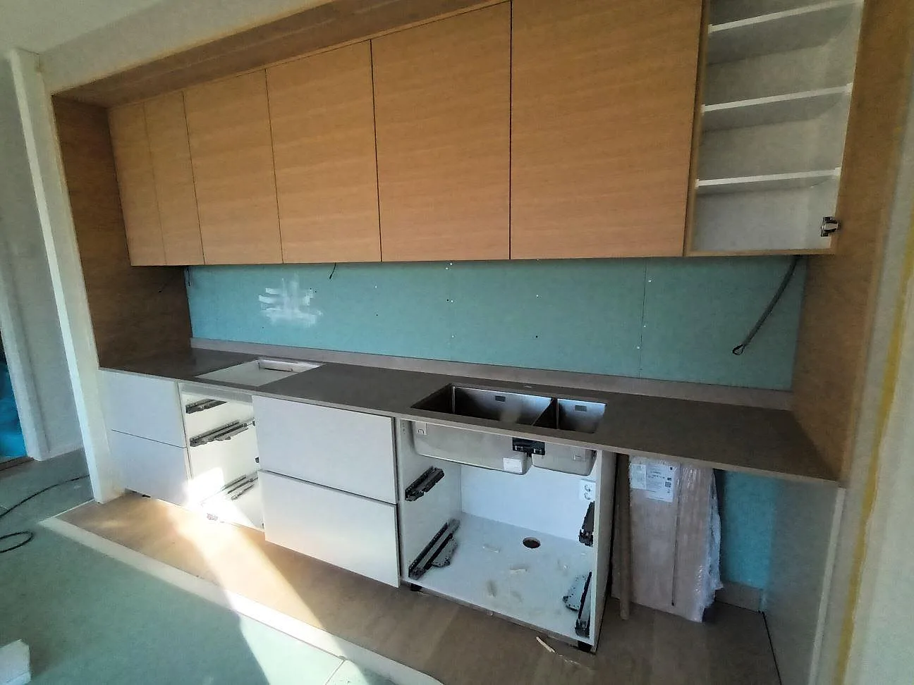 Köksbänkskiva i Silestone Coral Clay, polerad kvartskomposit, under montering i ett kök med träinredning och vita stommar i farsta.
