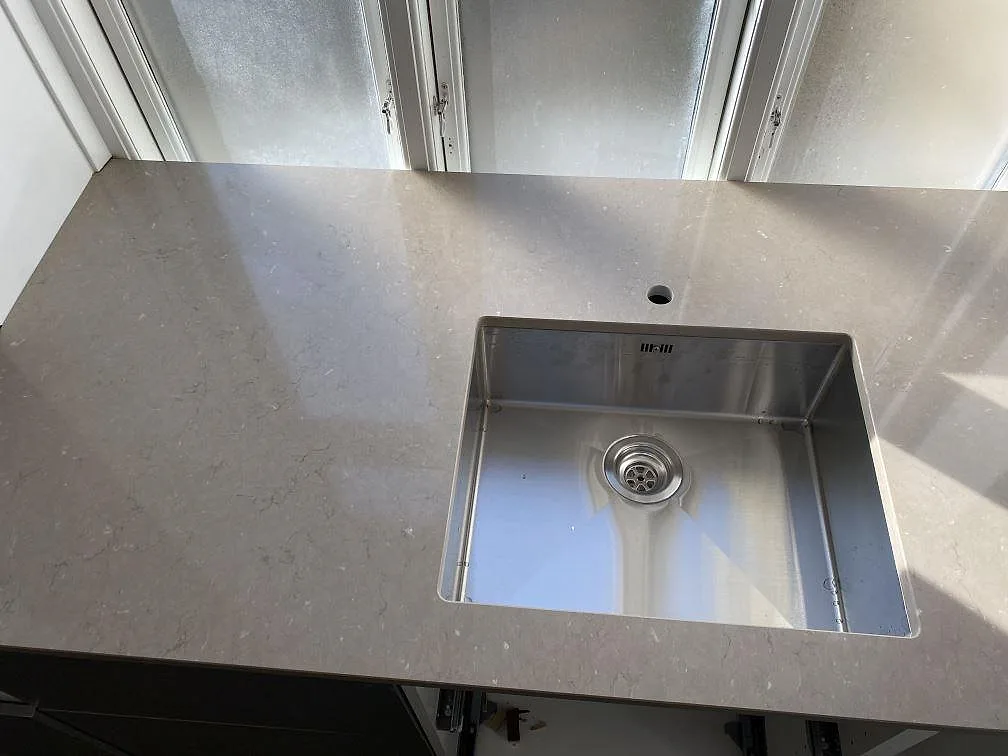 Diskbänksdel i polerad Silestone Coral Clay, komposit, med rostfri diskho och kranhål i kök i Frederiksberg c.