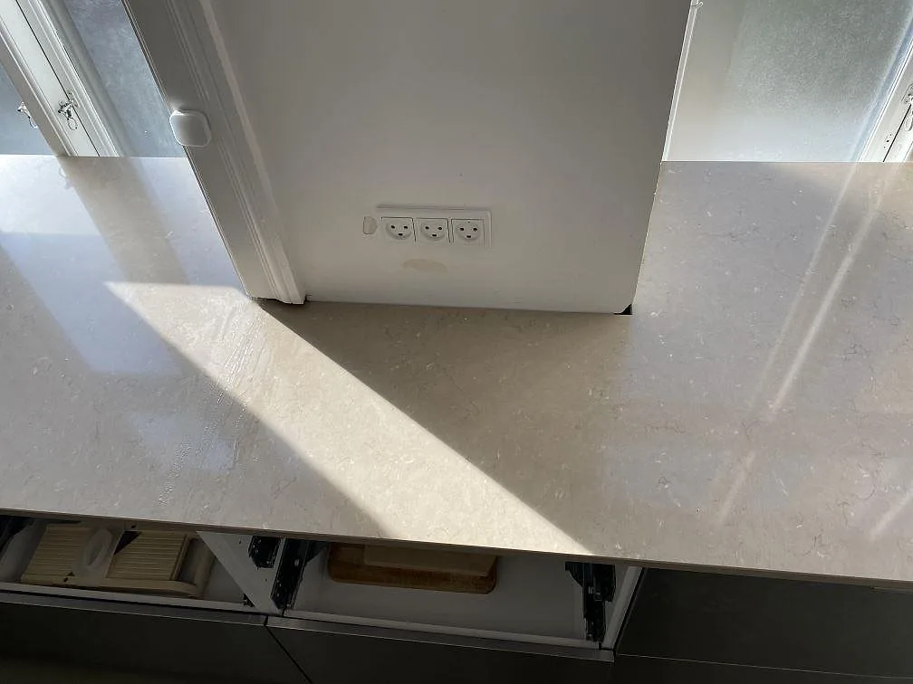 Sammanhängande arbetsyta i polerad Silestone Coral Clay, komposit, runt väggparti och eluttag i kök i Frederiksberg c.