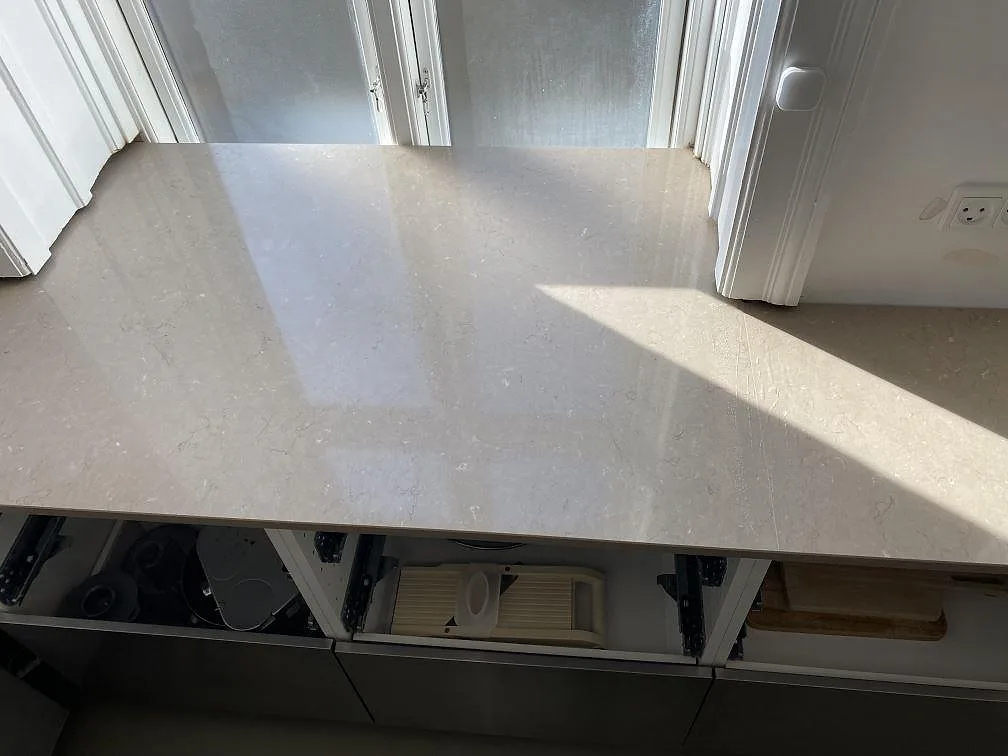Lång köksbänkskiva i polerad Silestone Coral Clay, komposit, med mjuk ådring vid fönster i Frederiksberg c.