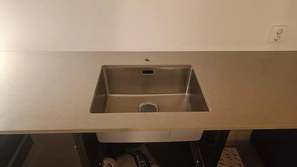 Närbild på rostfri diskho i en polerad bänkskiva av Silestone Coral Clay i ett kök i Gärsnäs.