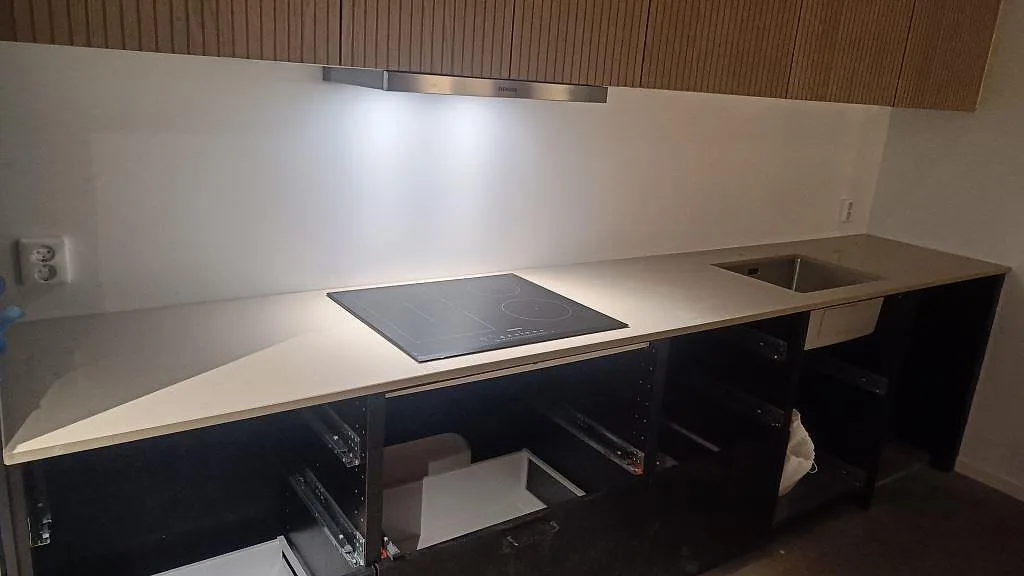 Köksbänkskiva i gråbeige Silestone Coral Clay, polerad komposit, med häll och rostfri diskho i ett kök i Gärsnäs.