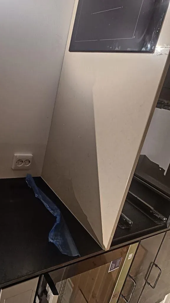 Köksbänk i Silestone Coral Clay sedd från sidan med induktionshäll och utskuret diskhohål, polerad kvartskomposit i ett kök i Gärsnäs.