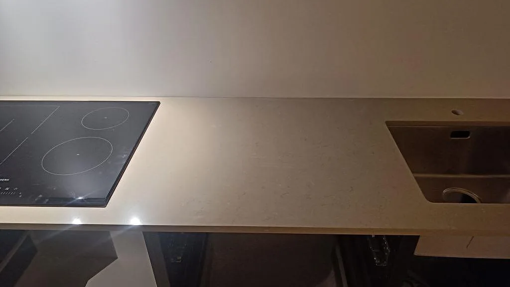 Köksbänkskiva i Silestone Coral Clay med induktionshäll till vänster och utskuret hål för diskho till höger, polerad yta i ett kök i Gärsnäs.