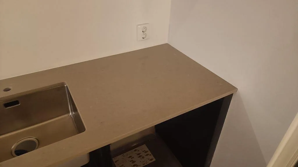 Vinklad vy av Coral Clay köksbänk med underlimmad rostfri diskho och varm lerbeige ton i ett kök i Gärsnäs.