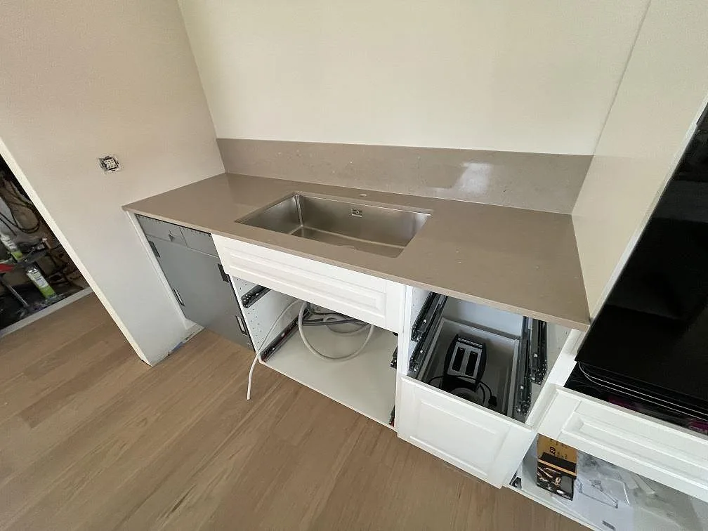 Polerad köksbänkskiva i Silestone Coral Clay med rostfri diskho och stänkskydd i ett kök i Gävle.