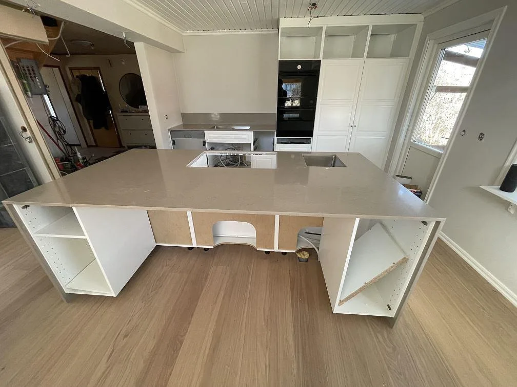 Polerad köksbänkskiva i beige Silestone Coral Clay med köksö och hällurtag i ett kök under montering i Gävle.