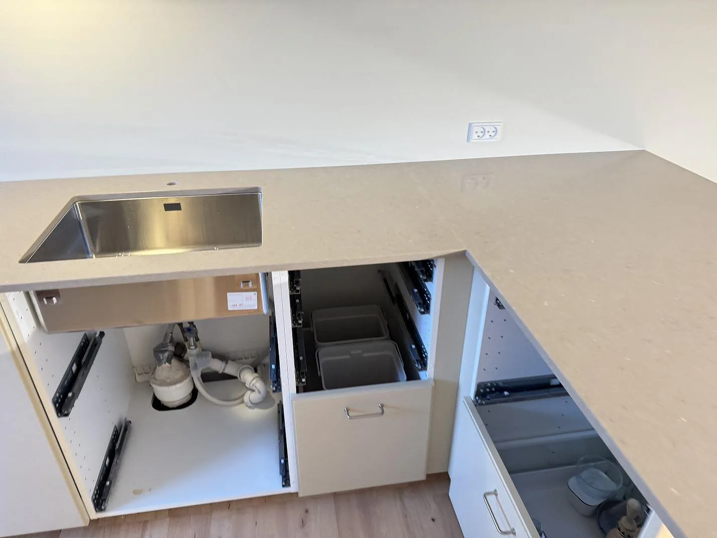 Köksbänkskiva i polerad Silestone Coral Clay med rostfri diskho, öppna lådor och sammanhängande arbetsyta i ett kök i Ganløse.