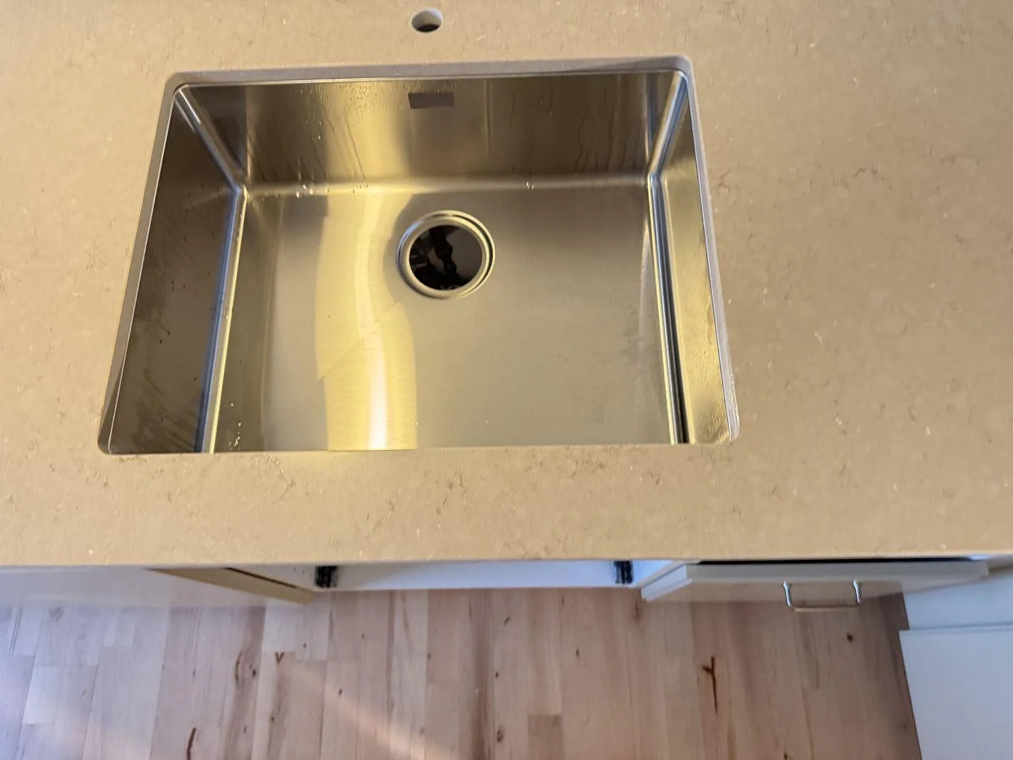 Närbild av rostfri diskho monterad i en köksbänkskiva i polerad Silestone Coral Clay i Ganløse.