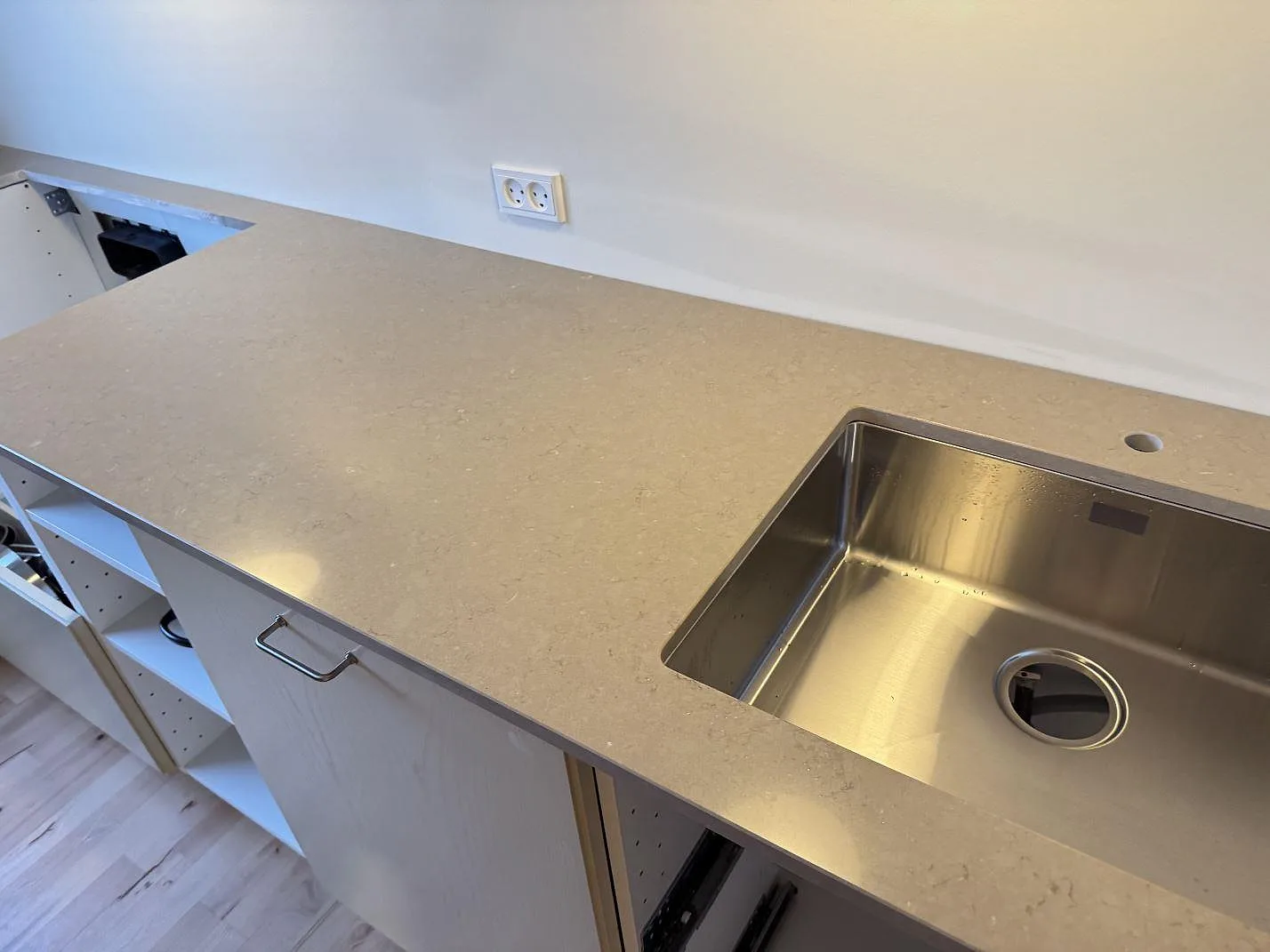 Polerad Silestone Coral Clay bänkskiva med rostfri diskho, kranhål och varm greige yta längs väggen i Ganløse.