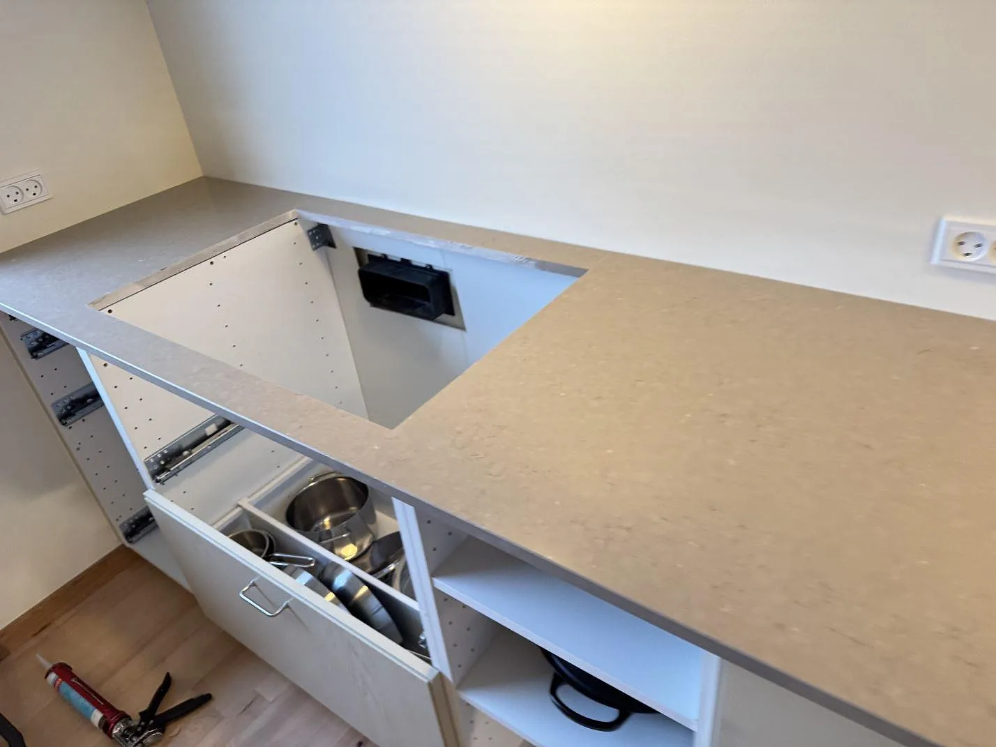 Köksbänkskiva i Silestone Coral Clay med rektangulärt urtag, polerad 20 mm kant och öppna skåpstommar under montering i Ganløse.