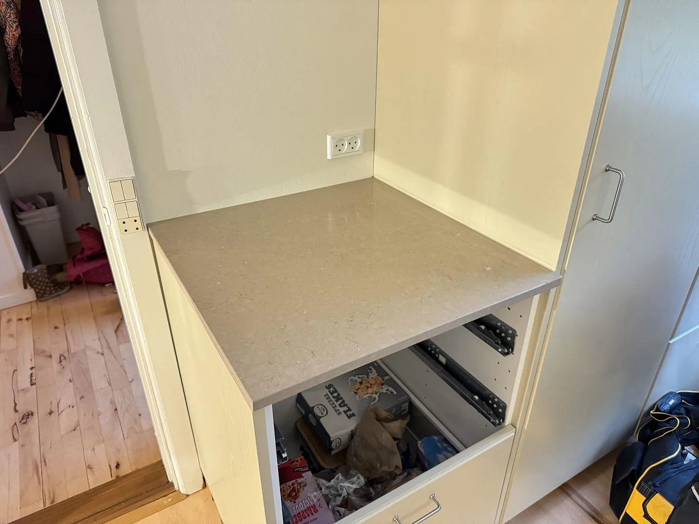 Kortare bänkdel i polerad Silestone Coral Clay mot vägg med eluttag och ljusa skåp i ett kök i Ganløse.