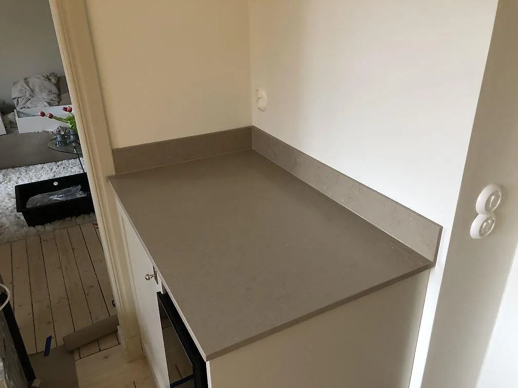 Köksbänkskiva i Silestone Coral Clay med uppvikt stänkkant i samma sten mot vit vägg i ett kök i Göteborg.