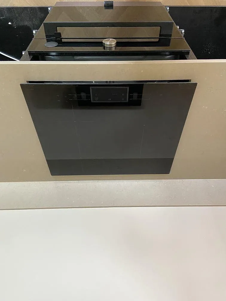 Infälld svart induktionshäll i greige Silestone Coral Clay köksbänkskiva med inbyggnadsugn under i ett kök i Göteborg.