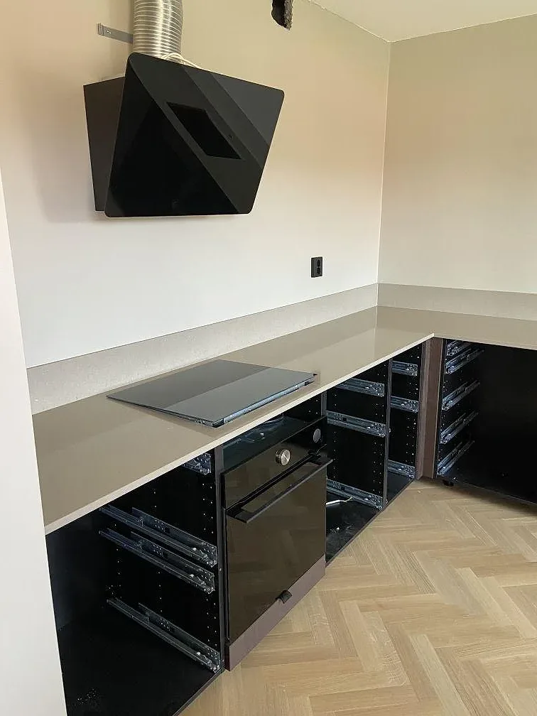 Översikt av köket under montering med köksö och svart fläkt intill Silestone Coral Clay bänkskiva i Göteborg.