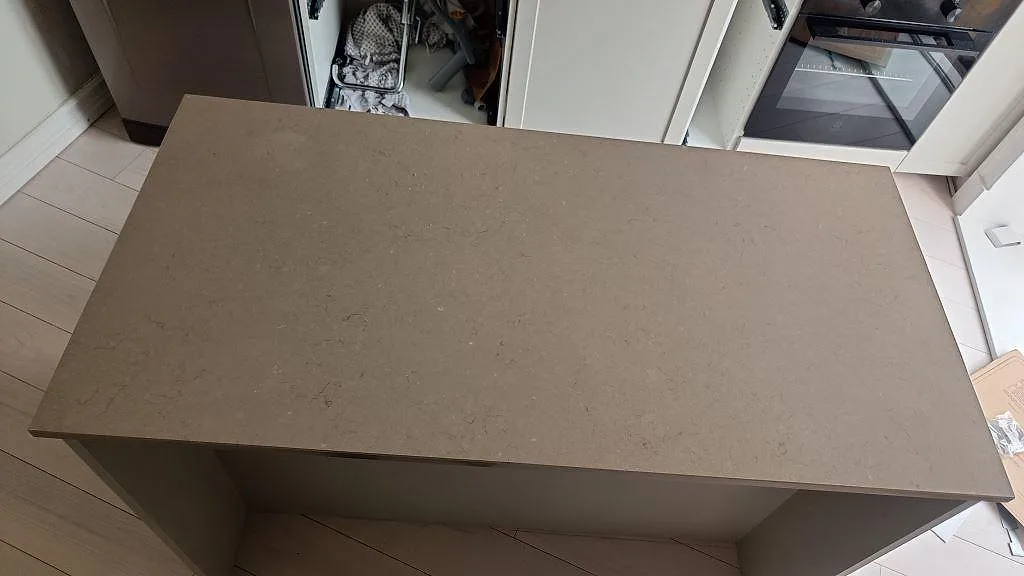 Närbild ovanifrån av köksö i polerad Silestone Coral Clay komposit med varm gråbeige yta i Göteborg.