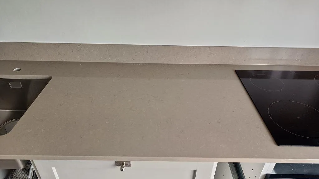 Lång köksbänkskiva i polerad Silestone Coral Clay komposit med diskho, häll och stänkkant i Göteborg.