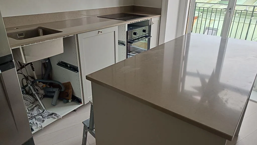 Polerad köksbänkskiva och köksö i Silestone Coral Clay komposit i ett kök under montering i Göteborg.