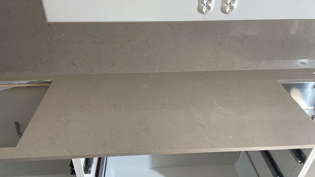 Detalj av rostfri diskho monterad under en polerad Silestone Coral Clay bänkskiva i komposit i Göteborg.