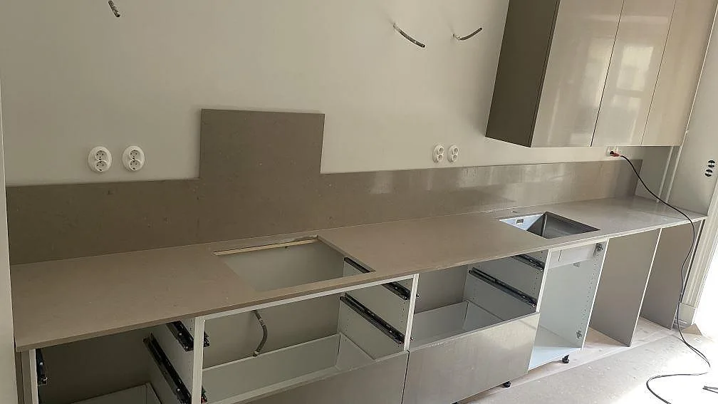 Polerad Silestone Coral Clay köksbänkskiva i komposit med stort diskhoutsnitt och gråbeige stänkskydd mot ljus vägg i Göteborg.