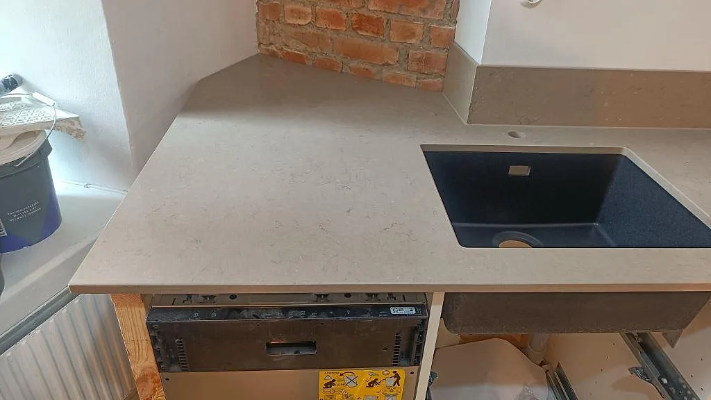 Bänkskiva i polerad Silestone Coral Clay med svart underlimmad diskho, öppen köksstomme och tegelvägg i Göteborg.