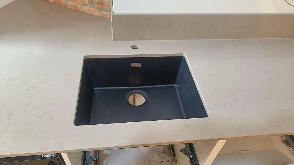 Närbild på svart underlimmad diskho i polerad Silestone Coral Clay med 12 mm stänkkant i ett kök i Göteborg.