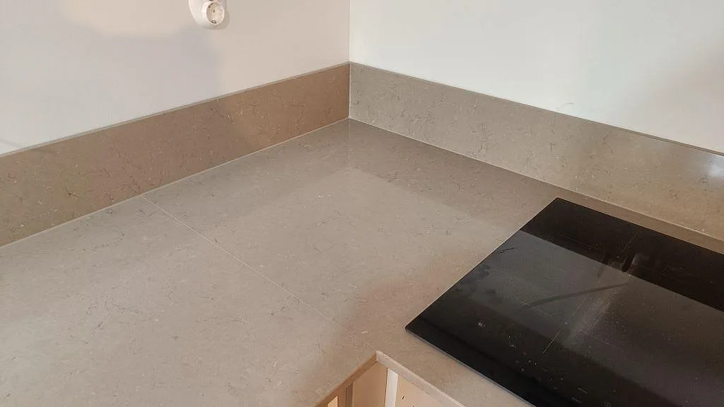 Hörndel i polerad Silestone Coral Clay med 12 mm stänkkant och svart induktionshäll i ett kök i Göteborg.