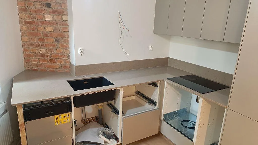 L-format kök i Göteborg med polerad Silestone Coral Clay som bänkskiva, svart underlimmad diskho, svart induktionshäll och uppvikt stänkkant.