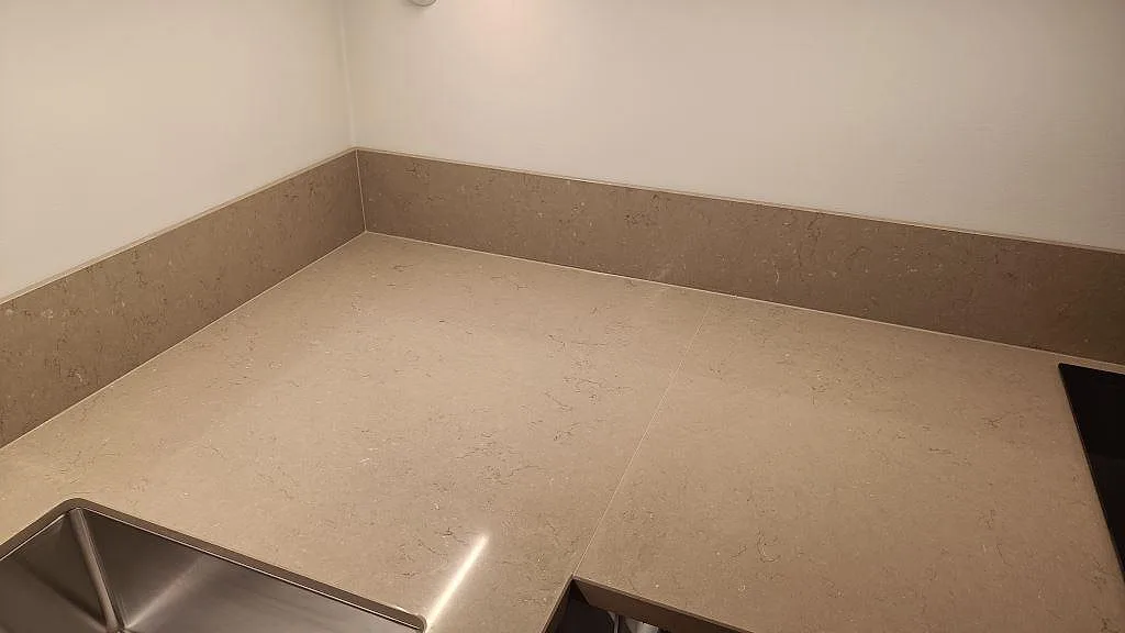 Närbild på den polerade Silestone Coral Clay ytan med stänkskydd, synlig diskho och hällkant i ett kök i Göteborg.