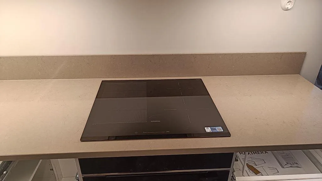 Polerad köksbänkskiva i Silestone Coral Clay med svart häll och låg stänkkant i ett kök i Göteborg.
