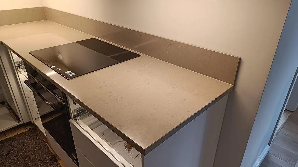 Sidovy av köksbänkskiva i Silestone Coral Clay, polerad gråbeige komposit, med hällzon och stänkskydd i Göteborg.