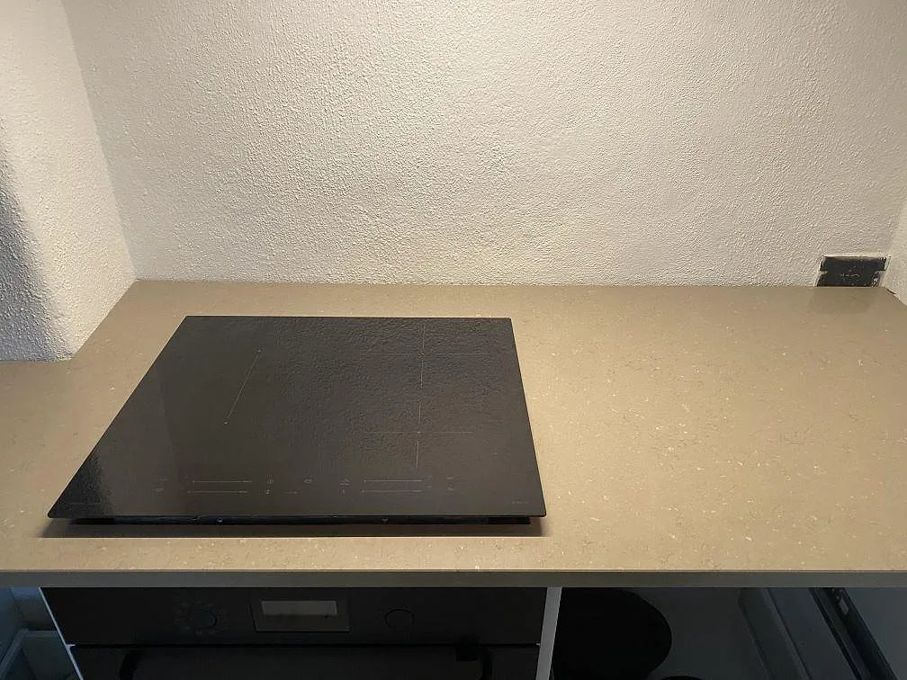 Köksbänkskiva i Silestone Coral Clay, polerad greige kvartskomposit, med infälld induktionshäll i ett kök i Grebbestad.