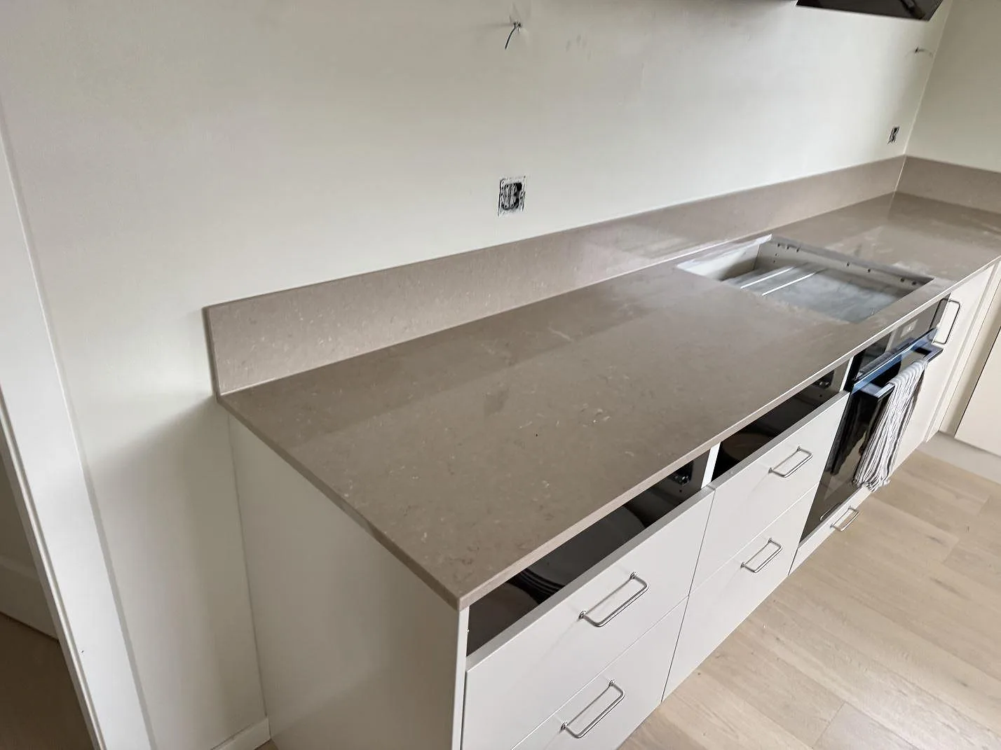 Köksbänkskiva i polerad Silestone Coral Clay komposit med stänkskydd och synligt hällurtag i Gullbrandstorp.