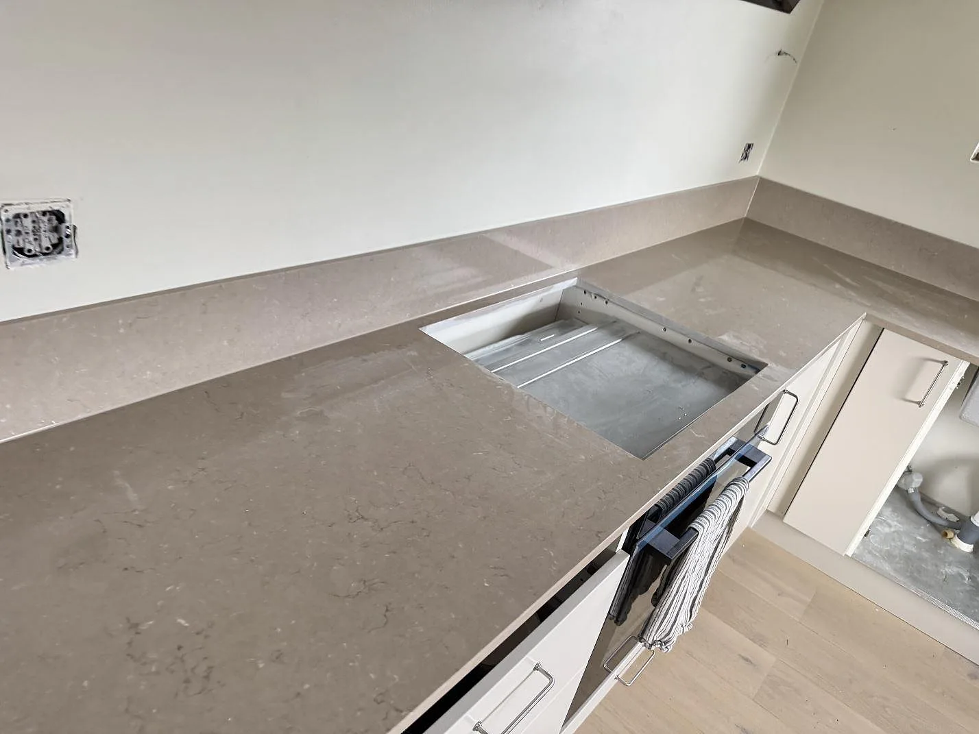 Polerad Silestone Coral Clay bänkskiva med hällurtag och låg stänkkant i ett kök i Gullbrandstorp.