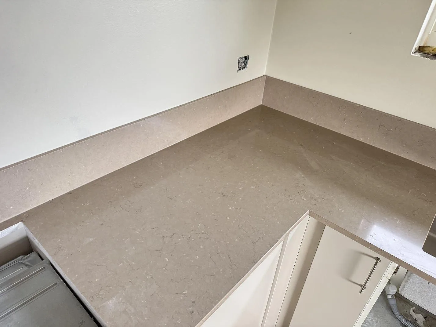 L-format hörn med polerad Silestone Coral Clay bänkskiva och uppvikt stänkskydd i kök i Gullbrandstorp.