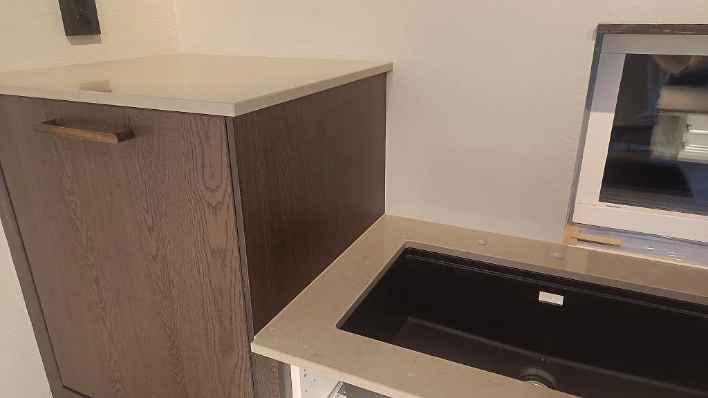 Diskbänk och sidobänk i polerad Silestone Coral Clay med mörk träinredning och svart diskho i Habo.
