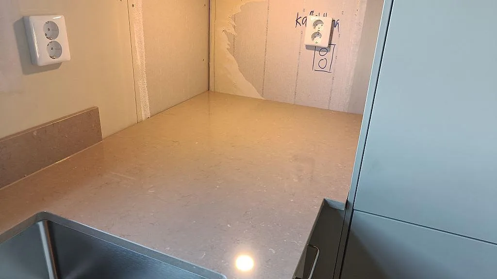 Närbild på polerad Silestone Coral Clay i Härryda med rostfri diskho, blank bänkyta och låg stänkkant i samma komposit.
